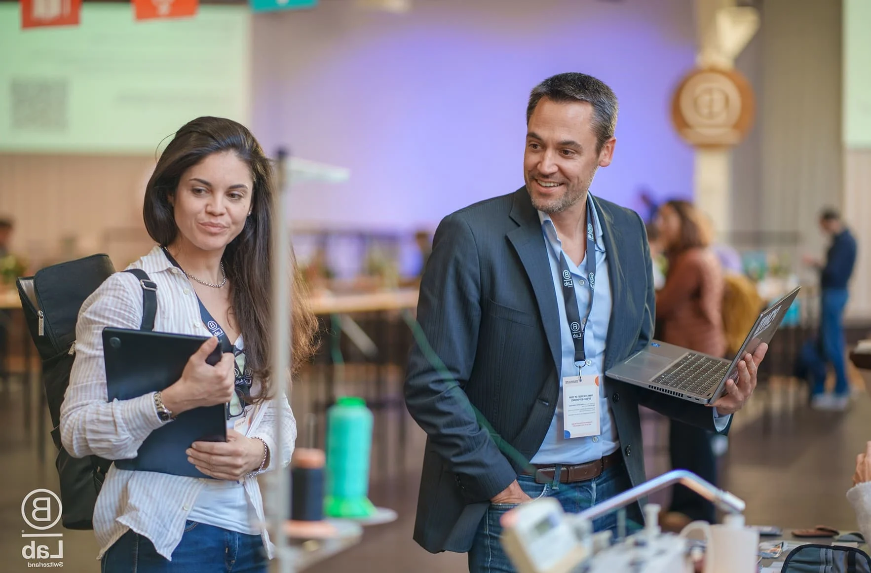Teilnehmende mit Tablet und Laptop im Gespräch bei einem Business Event im Eventforum Bern.