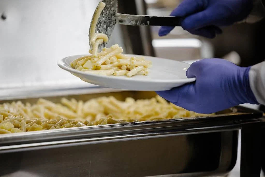 Warme Speisen werden am Buffet auf einen Teller geschöpft