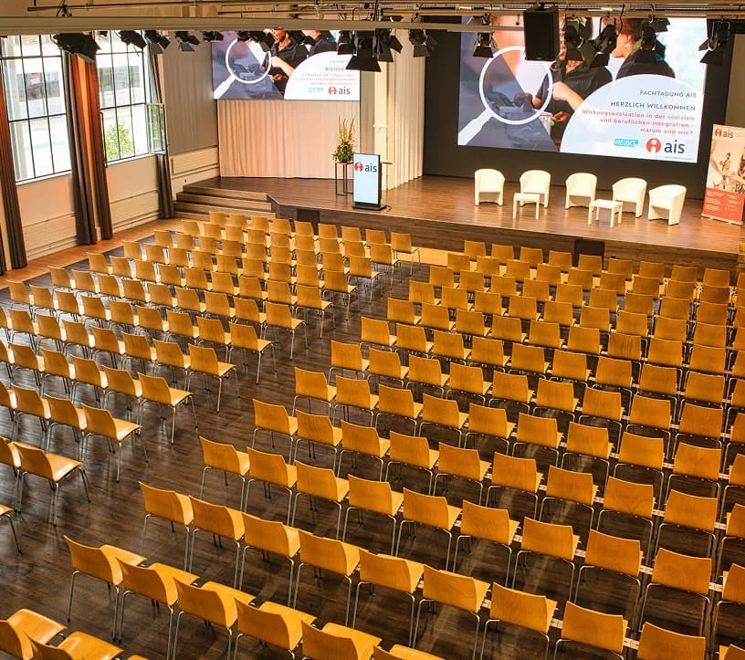 Bestuhlter Veranstaltungssaal mit Bühne und Präsentationstechnik im Eventforum Bern.