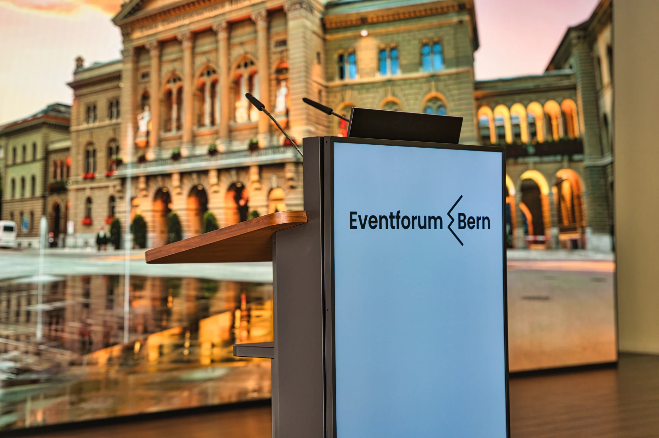 Lectern with a front monitor and microphones in front of the LED wall.