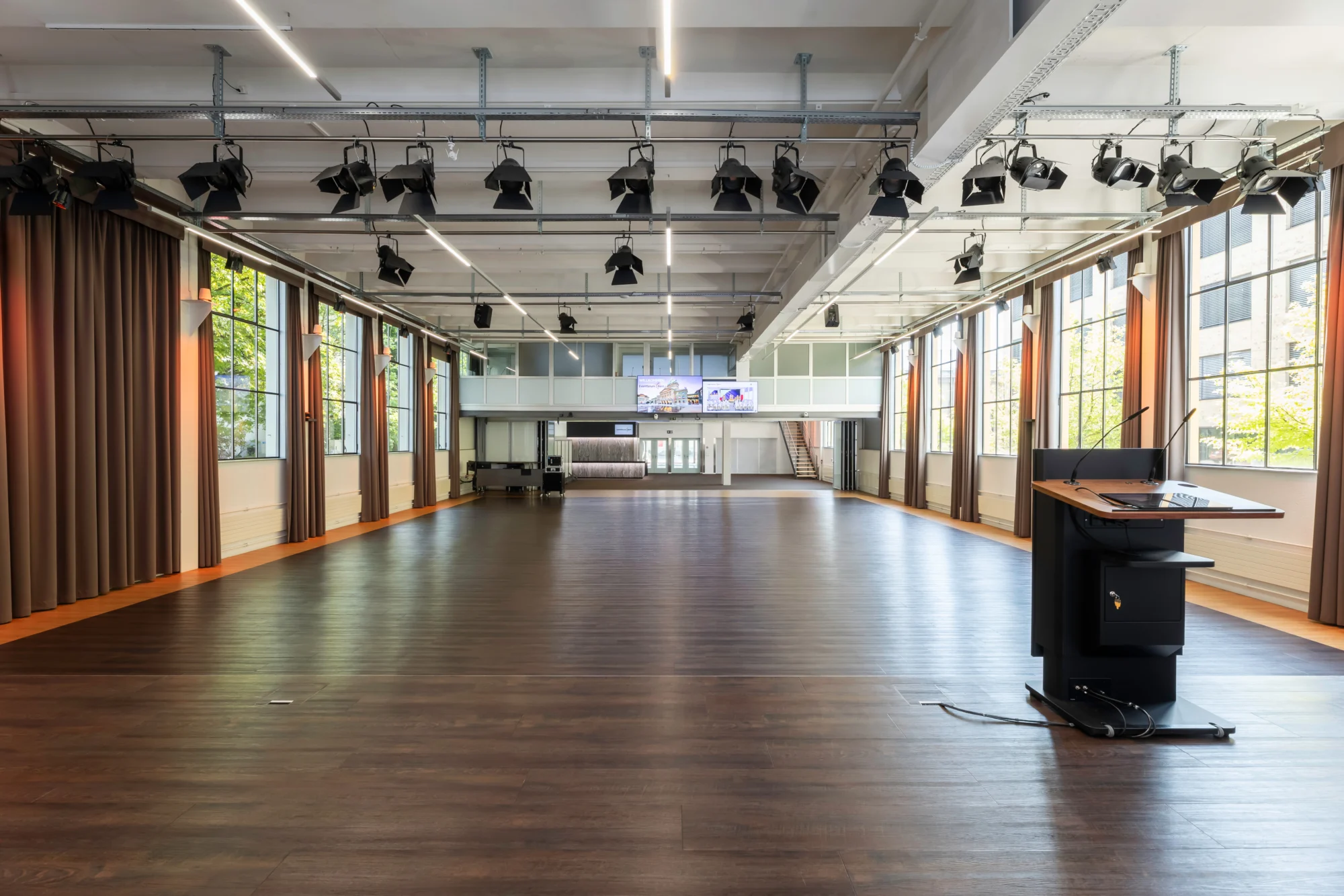 Blick von der Bühne über den Saal zur geöffneten Glas-Trennwand und zum hinteren Bereich im Eventforum Bern.