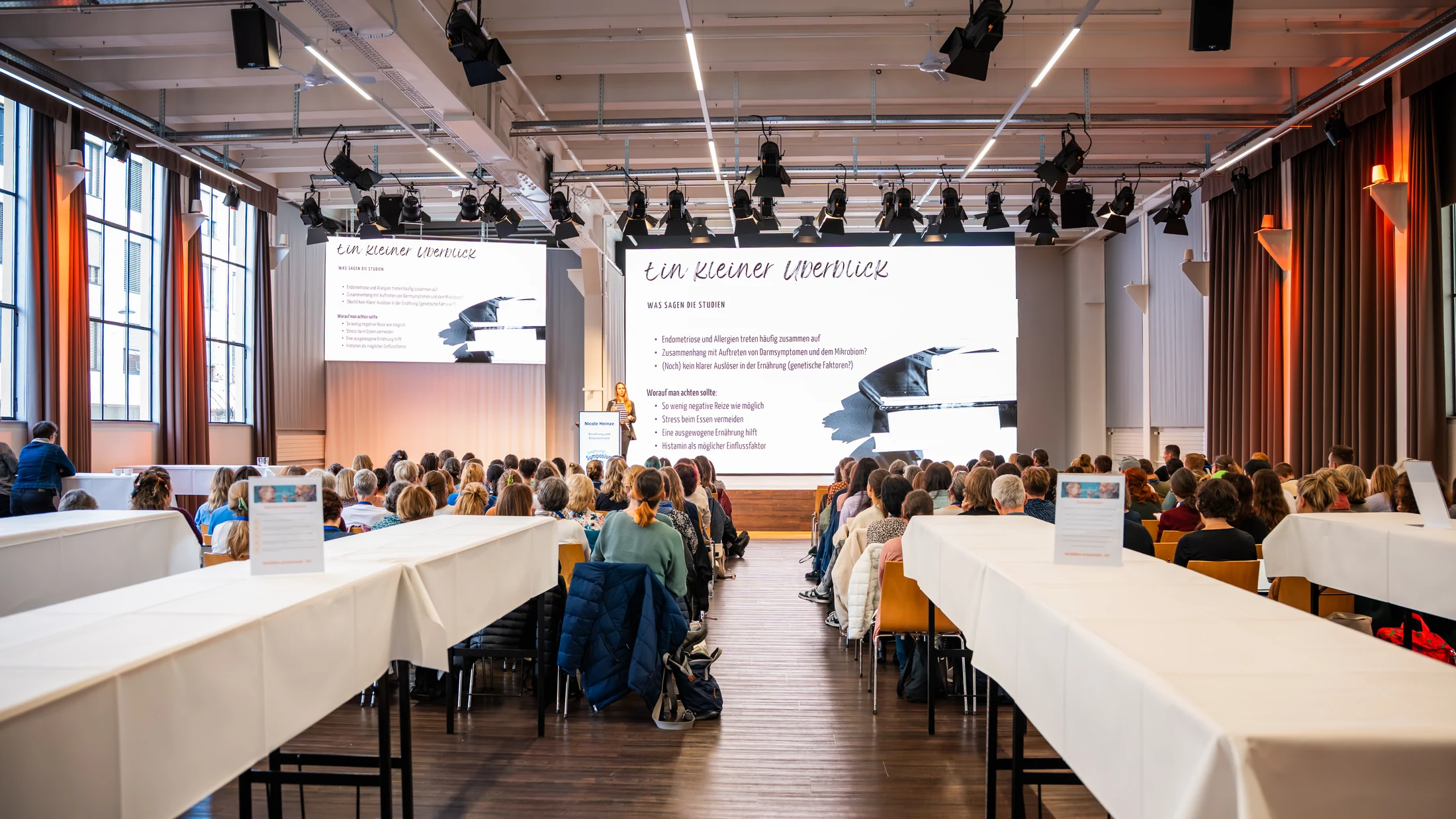 Seminar with a presentation and participants seated at tables at Eventforum Bern.