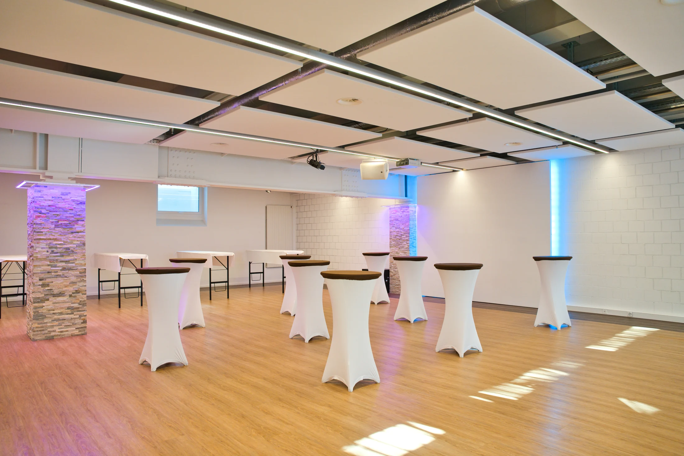 Flexible standing tables in bright workshop rooms with violet accent lighting.