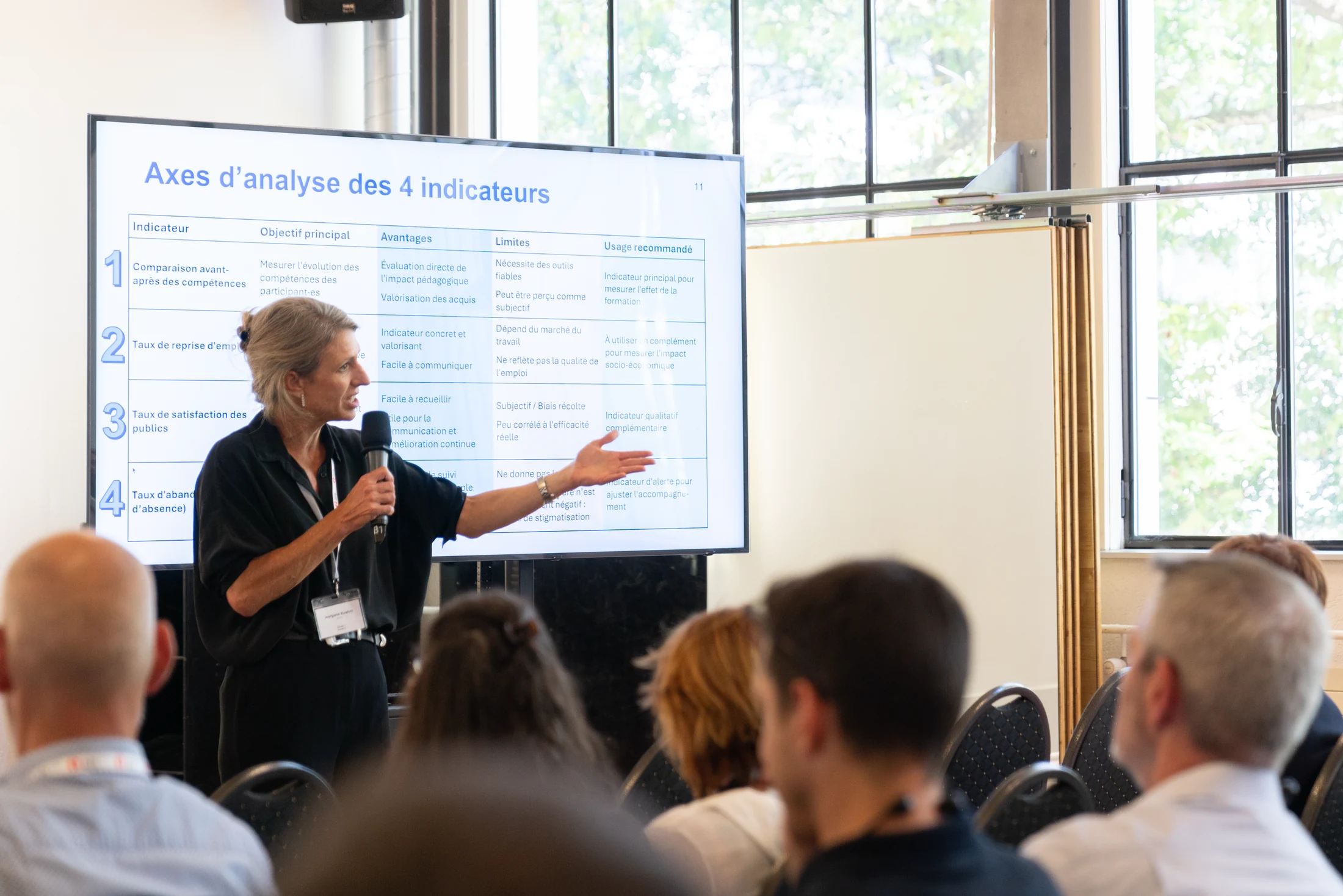 A speaker presenting at a screen to a workshop group.
