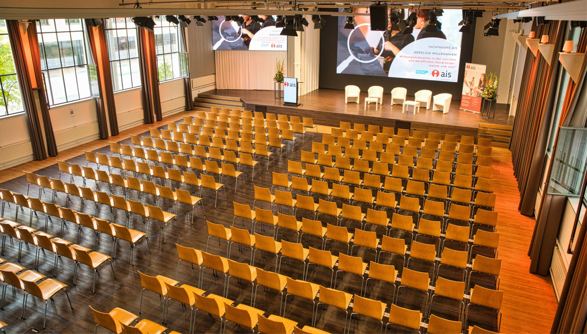 Eventhalle mit Reihenbestuhlung, Bühne und Präsentationsflächen im Eventforum Bern.