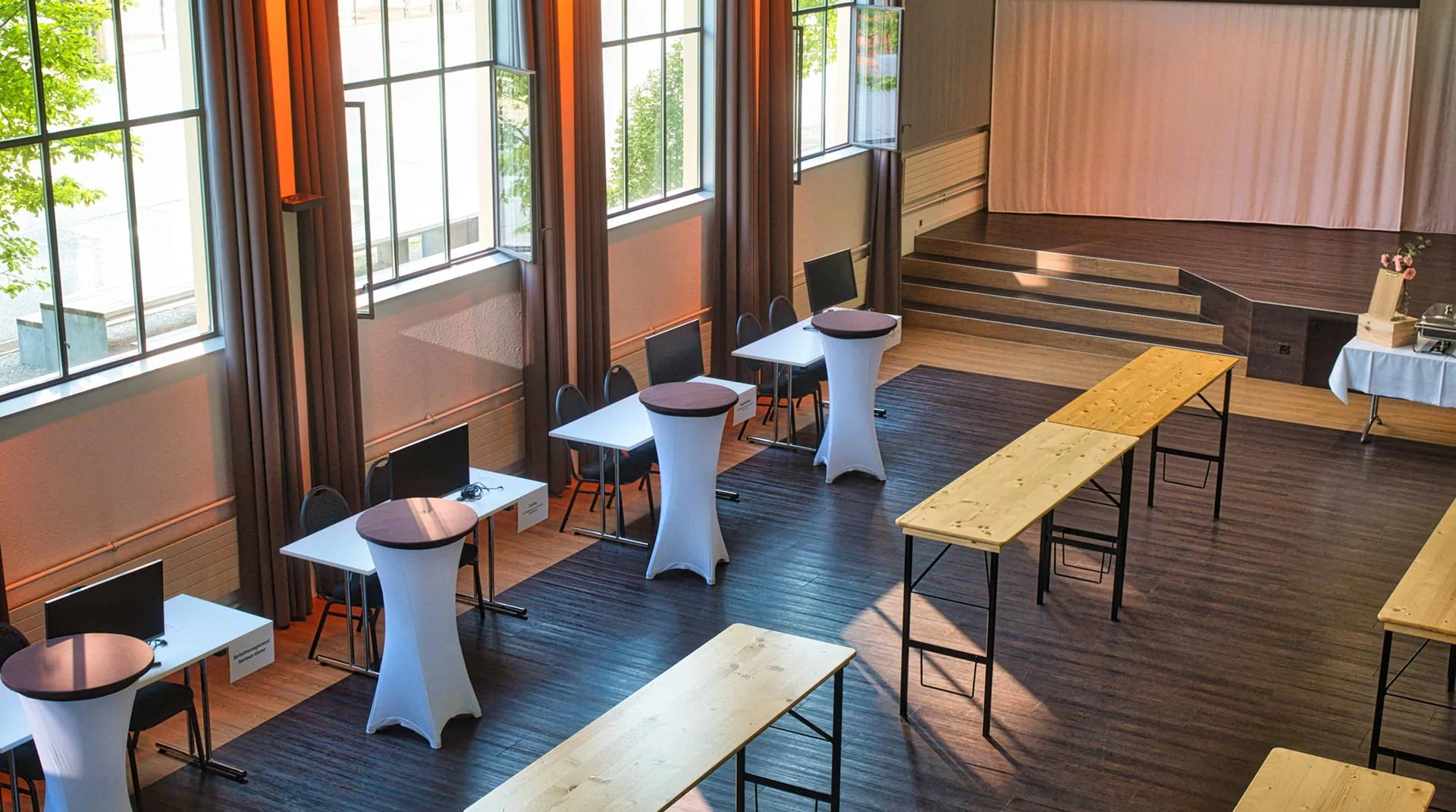 Eventhalle mit Stehtischen, Bänken und Bühne im Eventforum Bern.