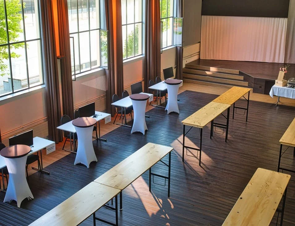 Eventhalle mit Stehtischen, Bänken und Bühne im Eventforum Bern.