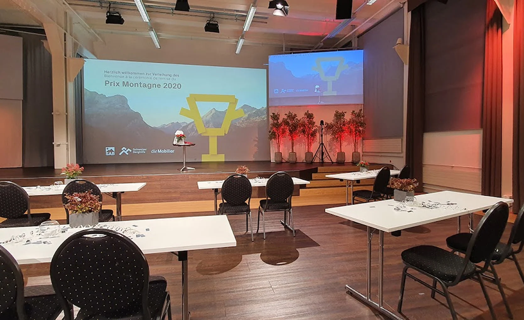 Eventhalle mit Tischbestuhlung, Bühne und Präsentationsflächen im Eventforum Bern.