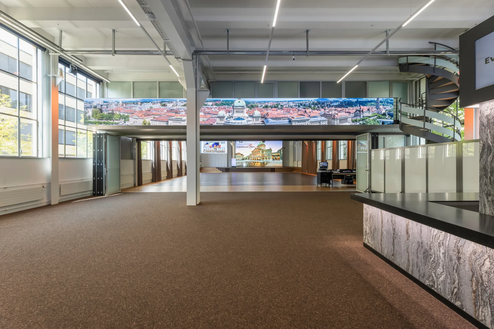 Foyer und Bistro im Eventforum Bern mit Empfangstheke, LED-Panoramaband und Blick in den Saal.