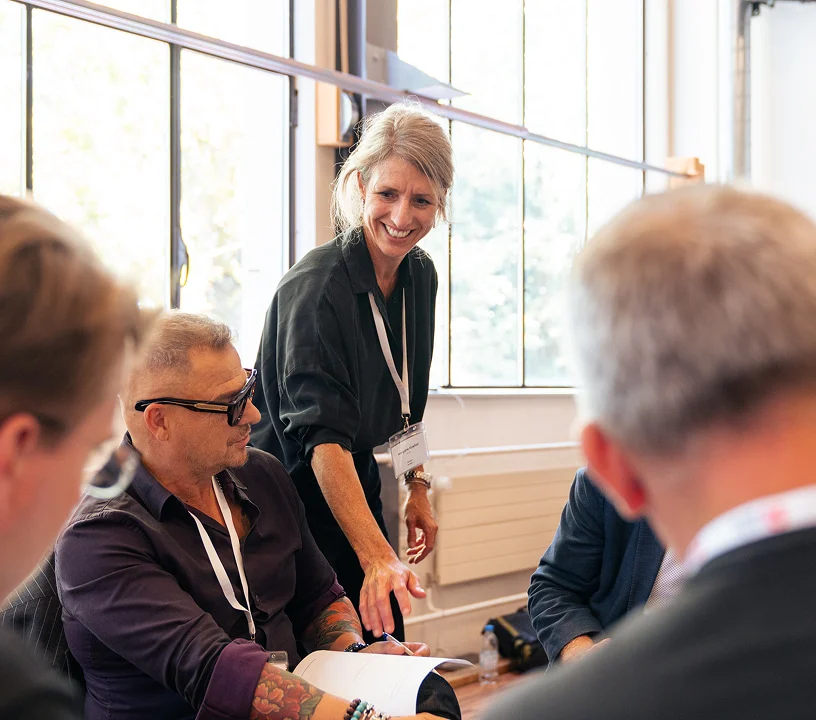 Teilnehmende arbeiten gemeinsam an Unterlagen während einer Konferenz im Eventforum Bern.