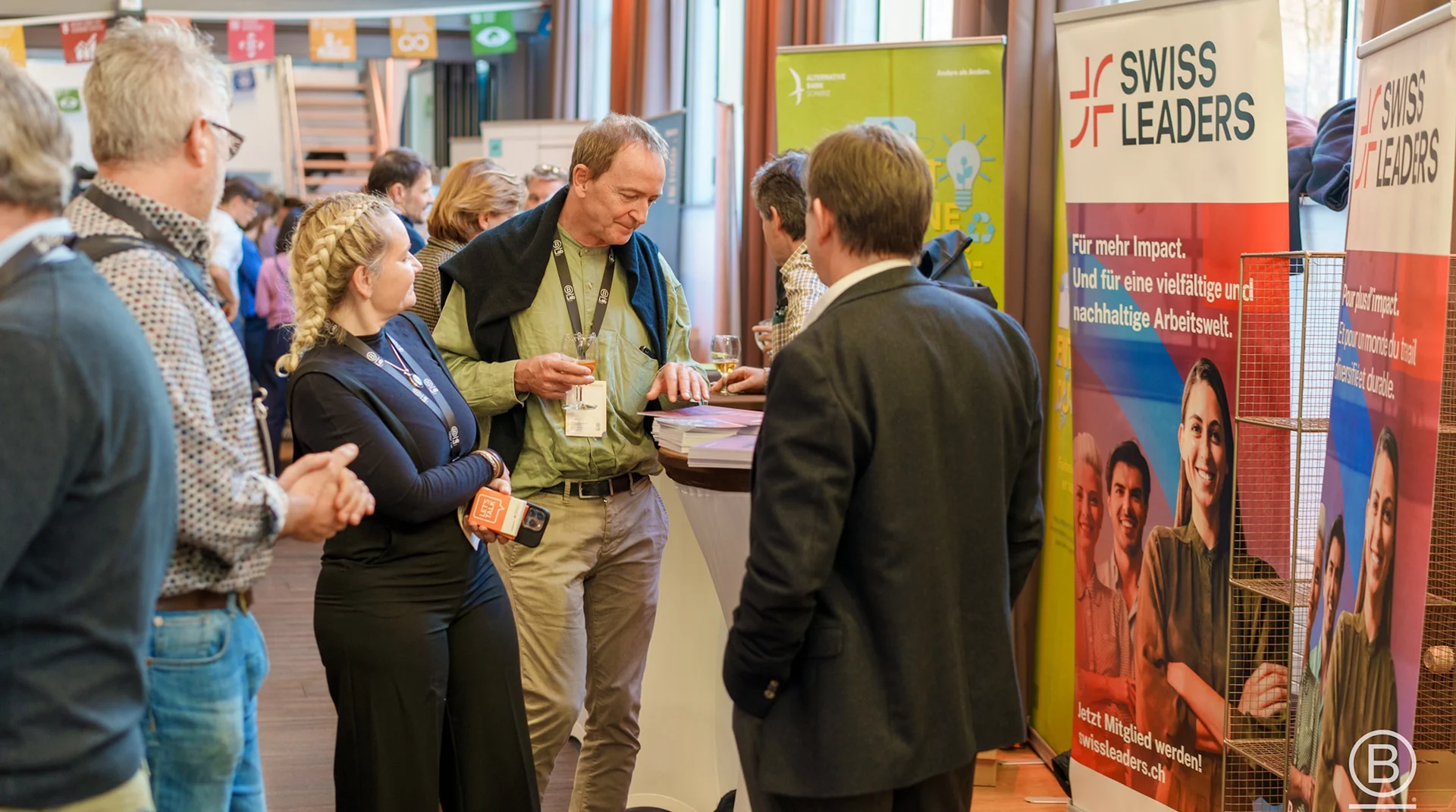 Teilnehmende im Gespräch an Informationsständen bei einer Veranstaltung im Eventforum Bern.