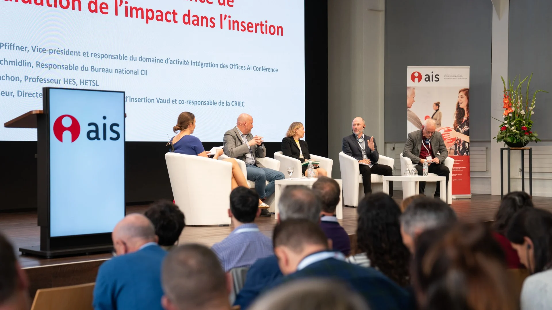 Podiumsdiskussion mit fünf Personen vor vollbesetztem Plenarsaal
