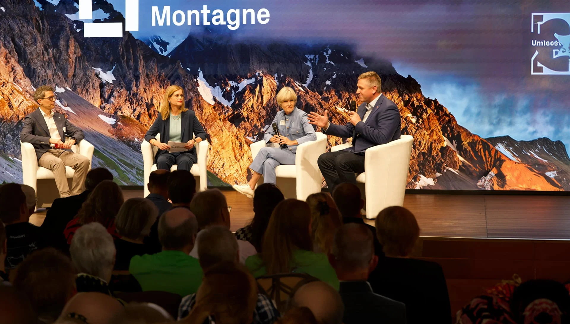Podiumsdiskussion vor Publikum mit grosser LED-Wand und Bergmotiv im Eventforum Bern.