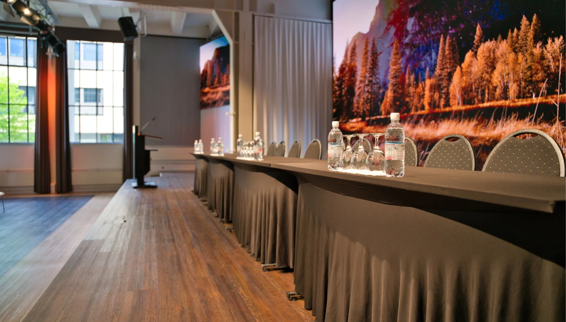 Podiumstisch mit Wasserflaschen und Gläsern vor LED-Wand im Eventforum Bern.
