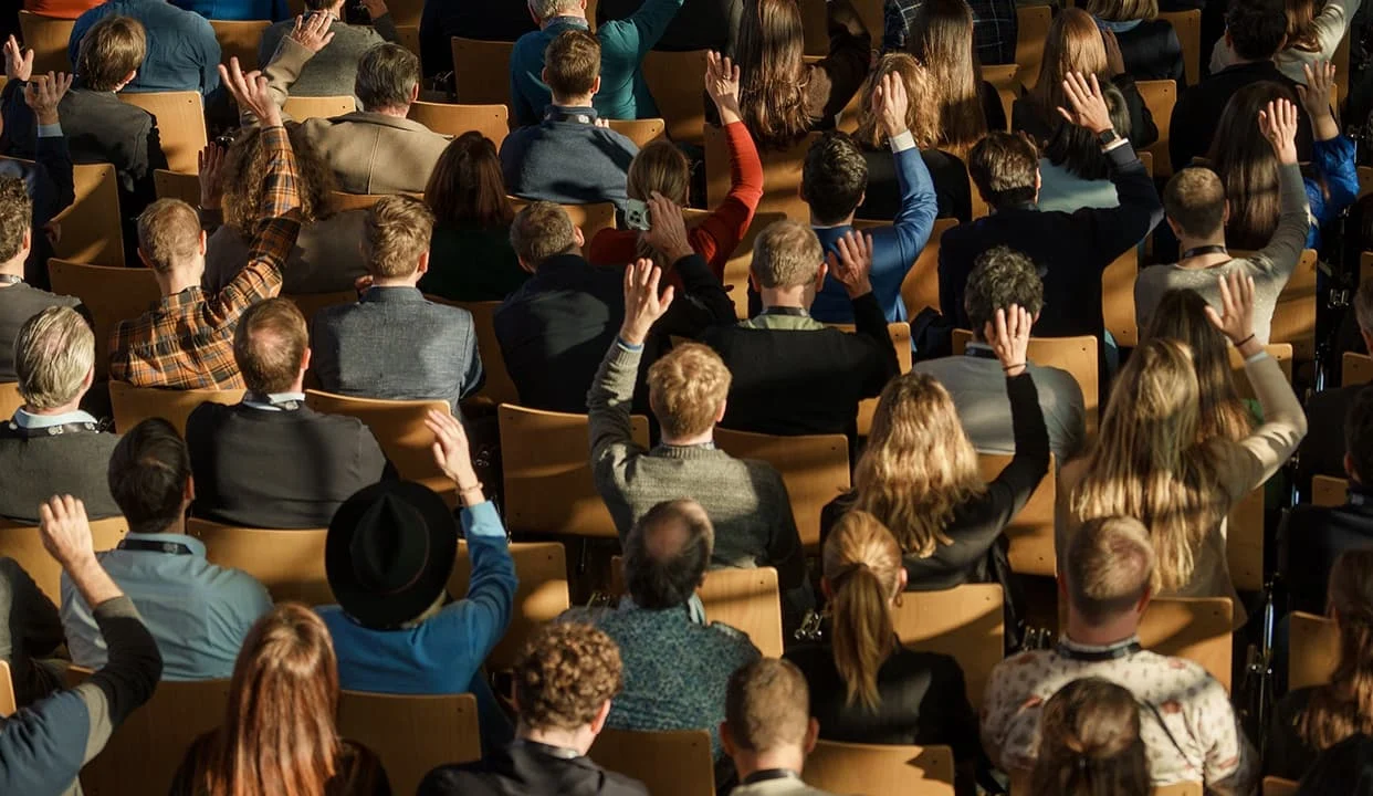 Publikum mit erhobenen Händen während einer Veranstaltung im Eventforum Bern.