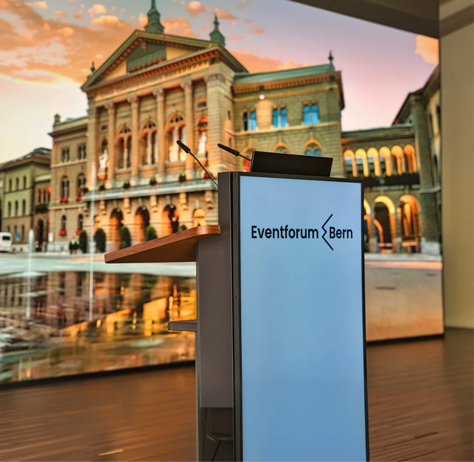 Rednerpult mit Eventforum-Bern-Logo vor einer grossen LED-Wand im Eventforum Bern.