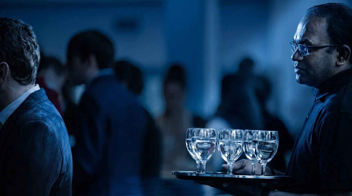 A member of the service team carrying a tray of water glasses during a drinks reception at Eventforum Bern.